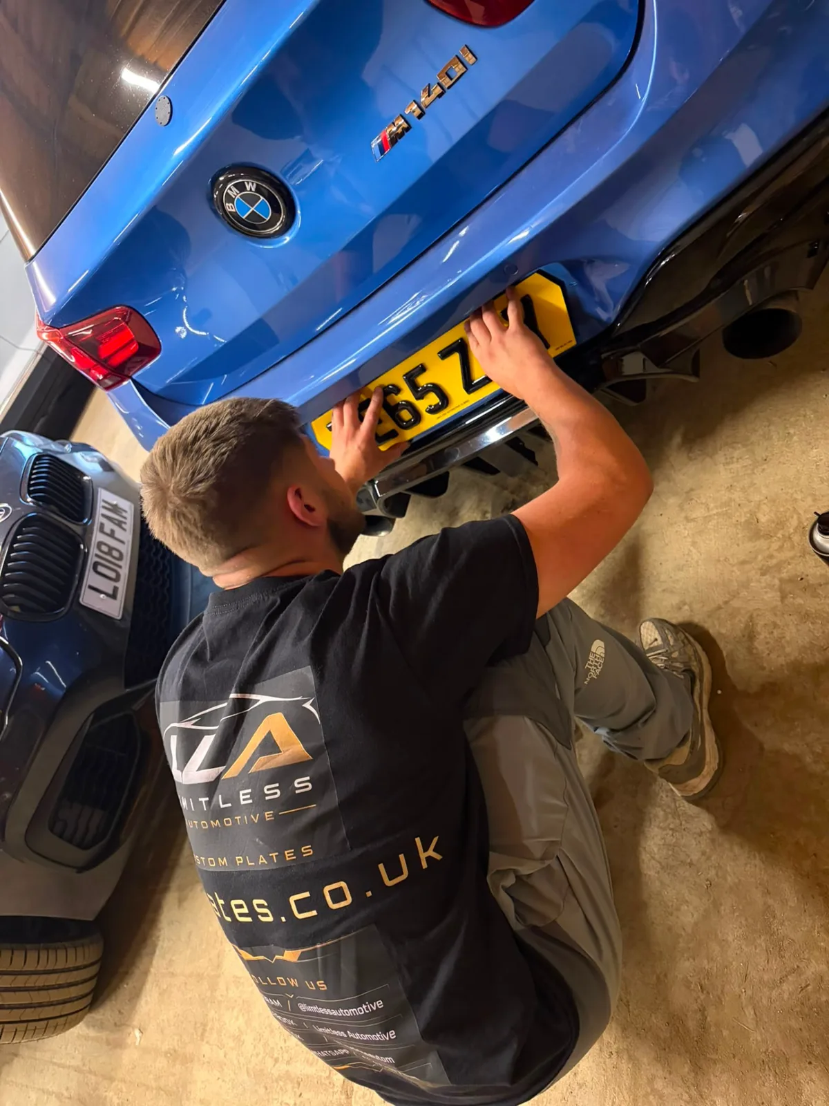 LLA Plates fitter installing a number plate on a blue BMW M140i